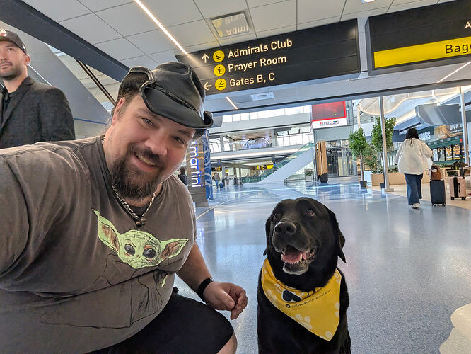 Selfie of hero in cowboy hat and Grogu shirt with Fergus the black Lab in PIT Paws bandana